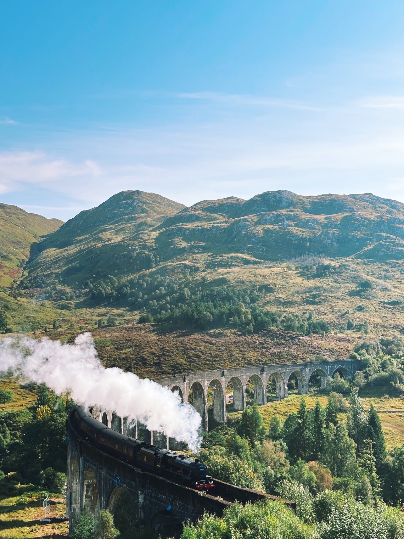 A steam train crossing the Glenfinnan viaduct through the Scottish Highlands